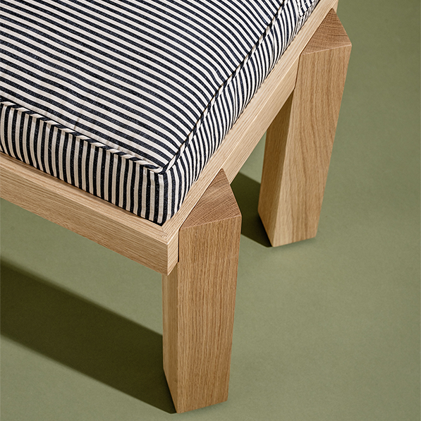 Wooden bench with striped cushion on a green background