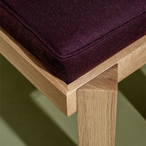 Wooden bench with a dark purple cushion on a green background