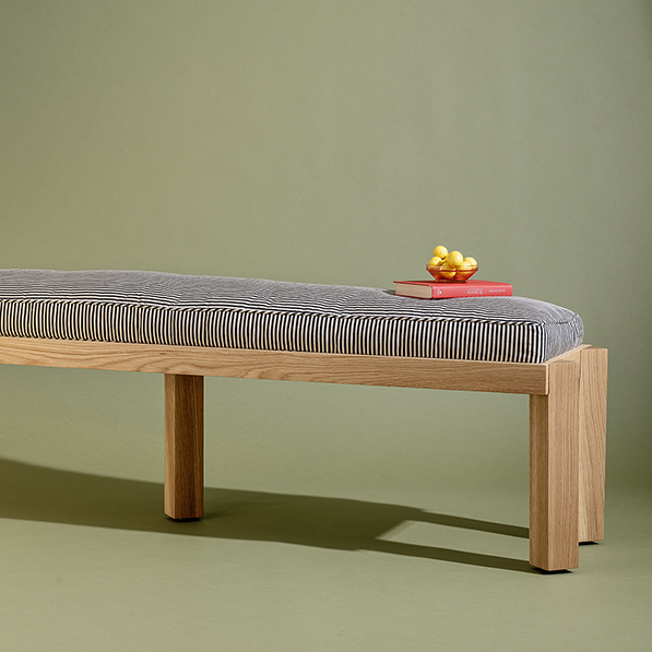 Wooden bench with striped cushion on a green background