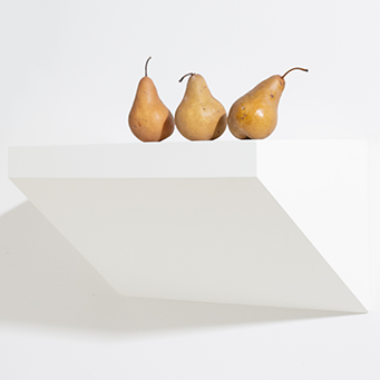 Three pears on a white geometric shaped shelf against a white background