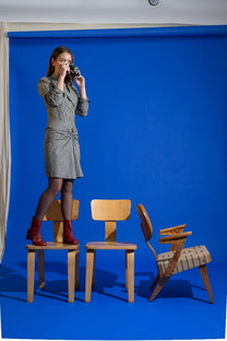 Woman standing on chairs against a blue backdrop