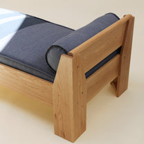 White oak daybed with a denim like cushion on a light background