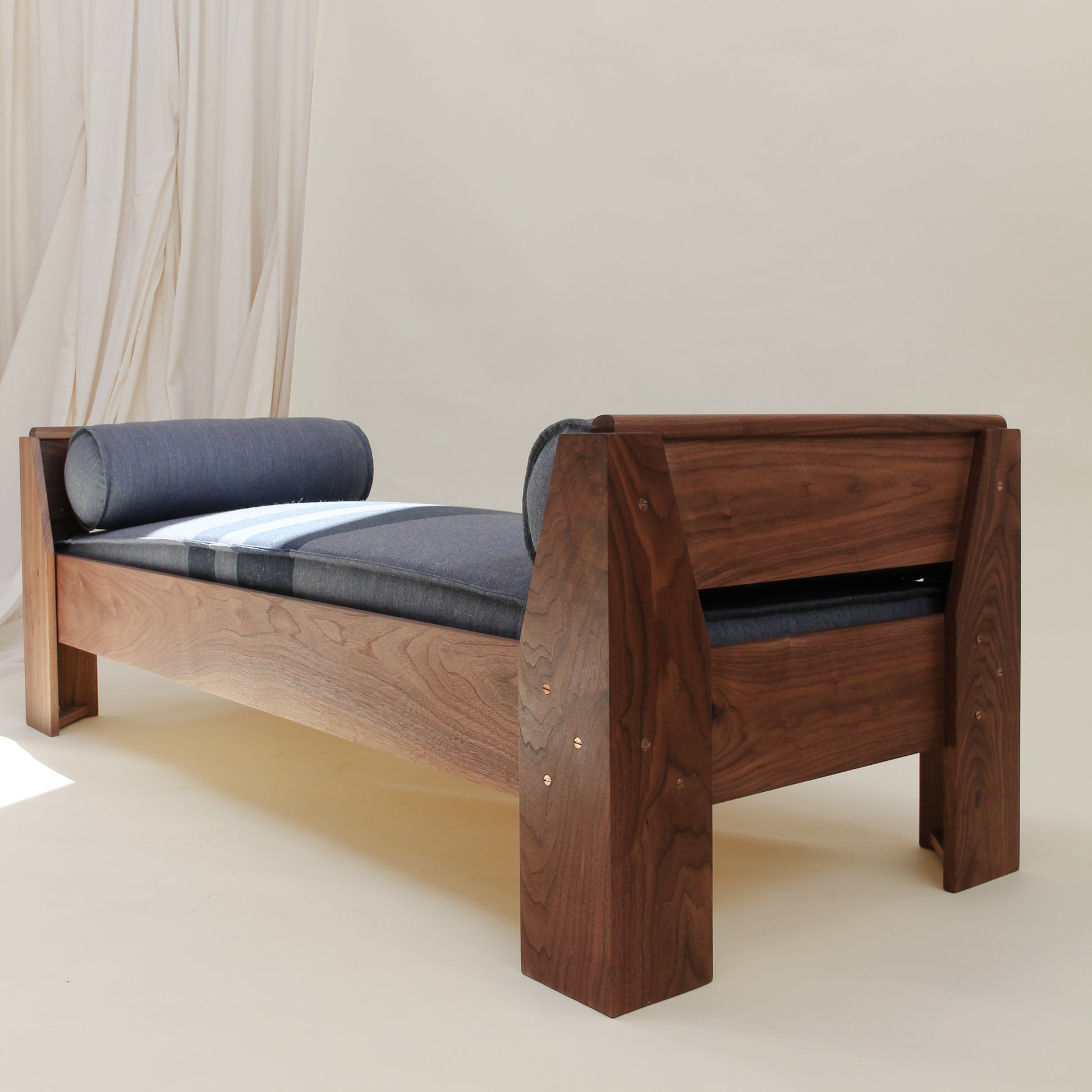 Wooden bench with blue cushion on a plain background