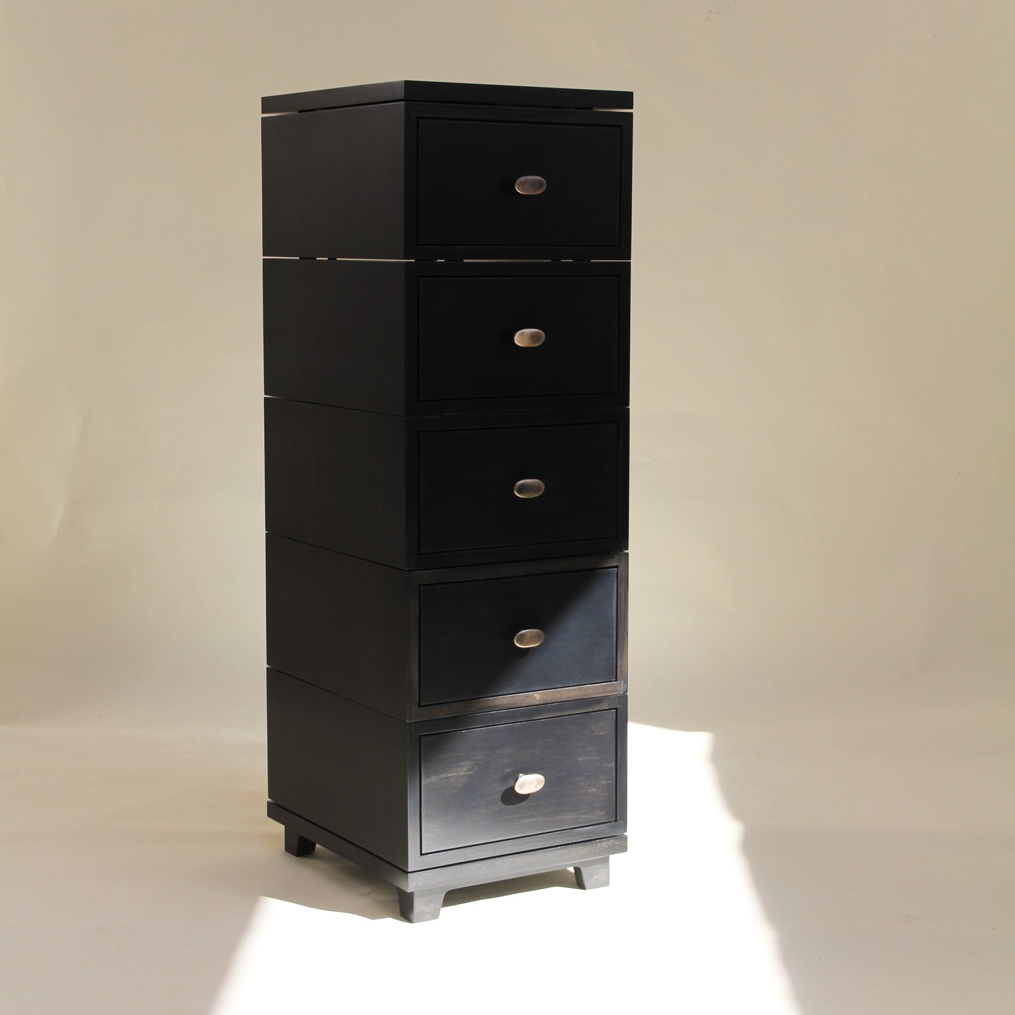 Black tall cabinet with multiple drawers on a beige background
