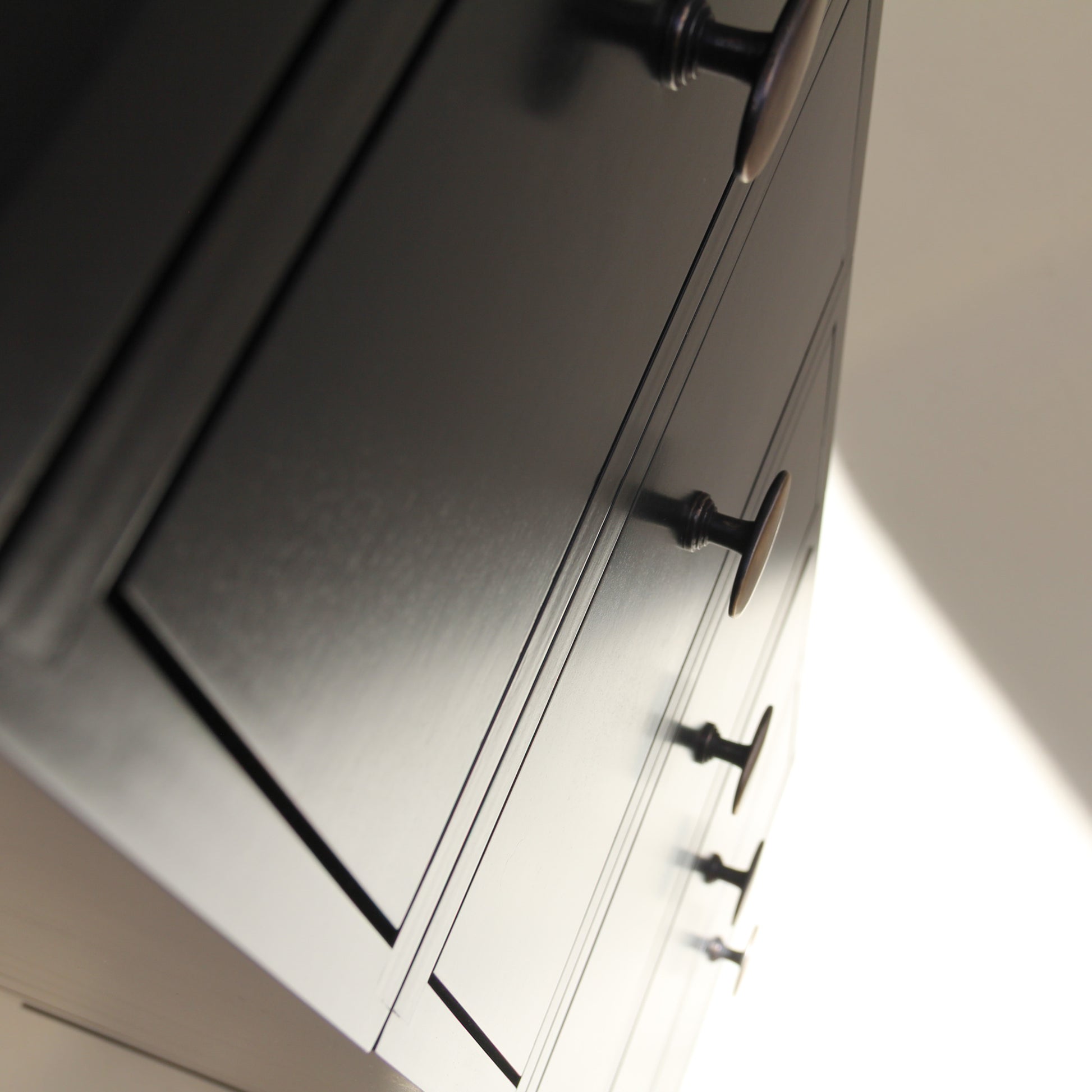 Close-up of a cabinet with black handles on a neutral background