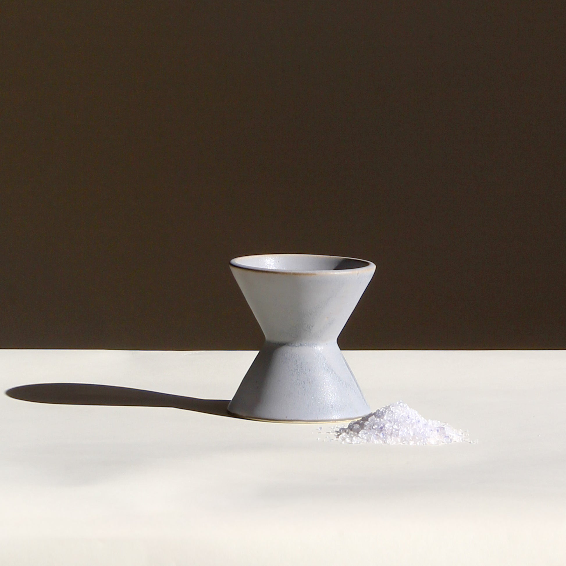 Ceramic white vase on a white surface with a brown background
