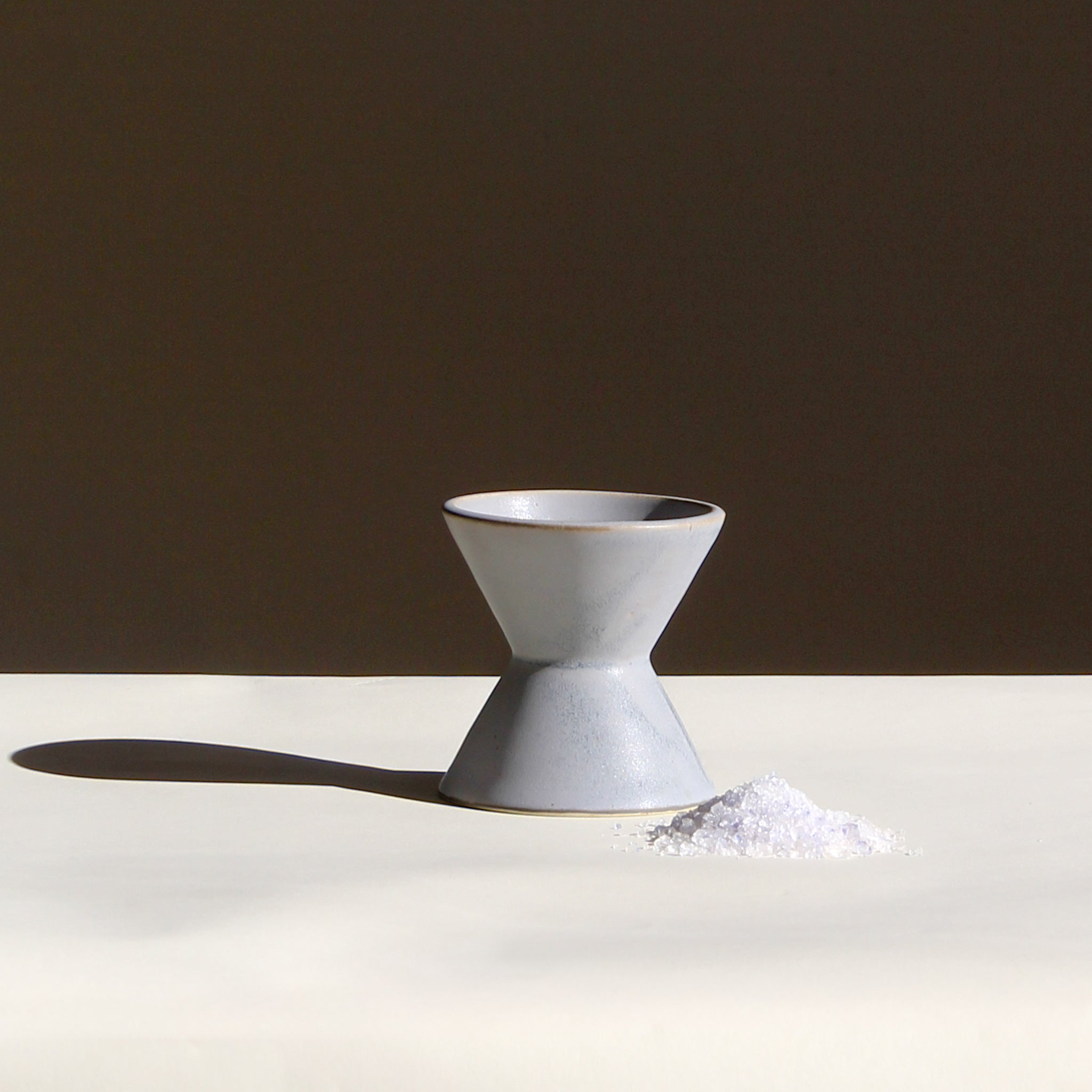 Ceramic white vase on a white surface with a brown background