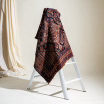 Decorative patterned blanket draped over a white ladder against a neutral background