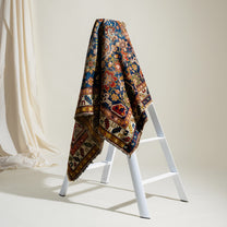 Colorful patterned rug draped over a white ladder against a neutral background
