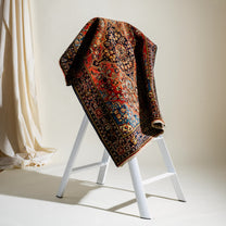 Decorative rug draped over a white ladder against a neutral background