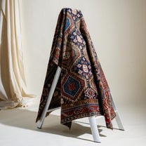 Decorative rug draped over a white ladder against a neutral background
