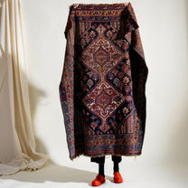 Person holding up a patterned rug over their body against a white background