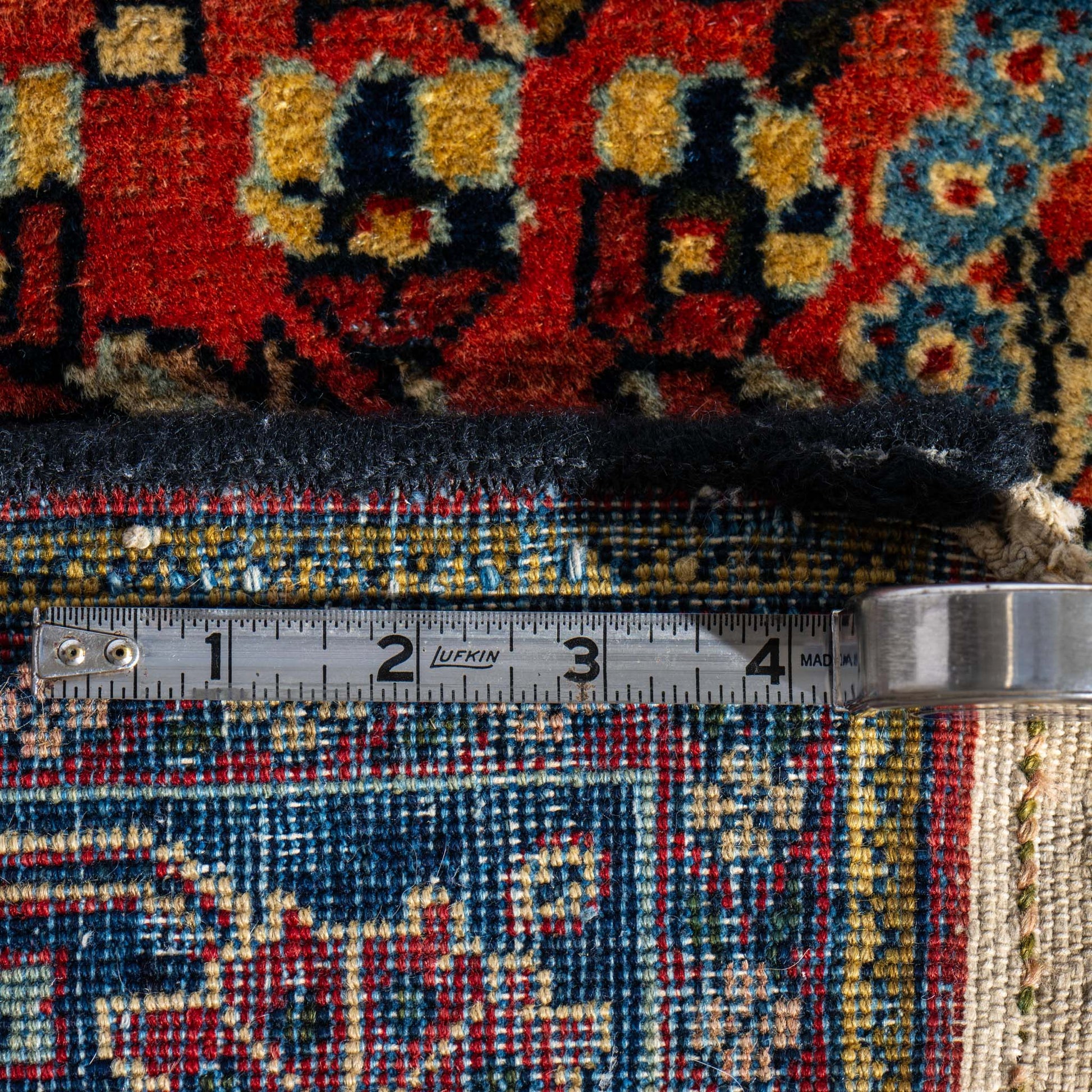 Close-up of a colorful rug with a measuring tape laid across it