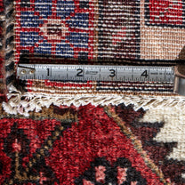 Rug with a measuring tape showing dimensions, close-up of patterned rug corner.