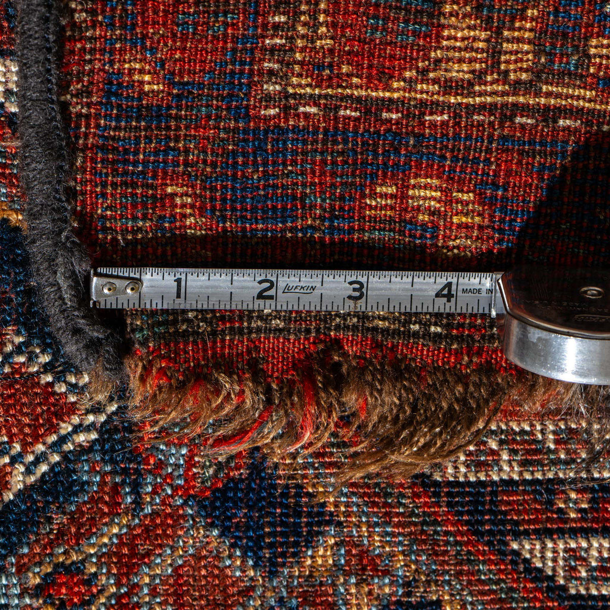 Close-up of a textured rug with a measuring tape laid across it