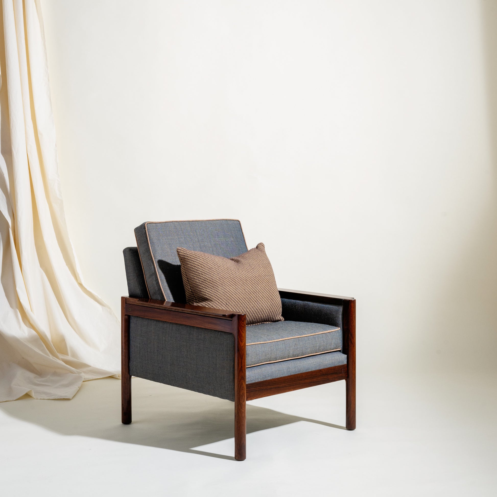 Modern armchair with wooden frame and gray cushions against a white background