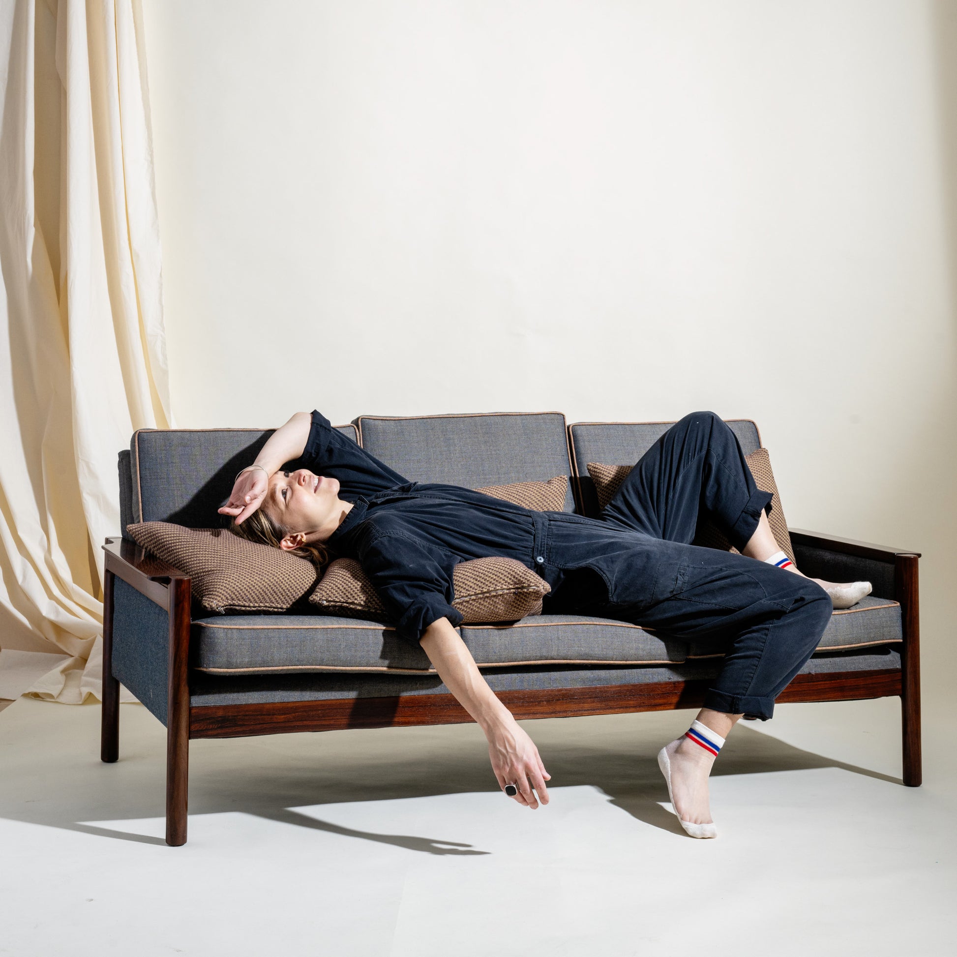 Person lying on a modern sofa with a neutral background