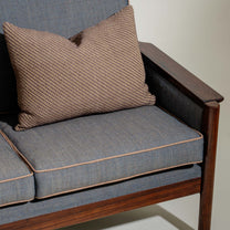 Gray cushioned chair with a brown textured pillow on a plain background
