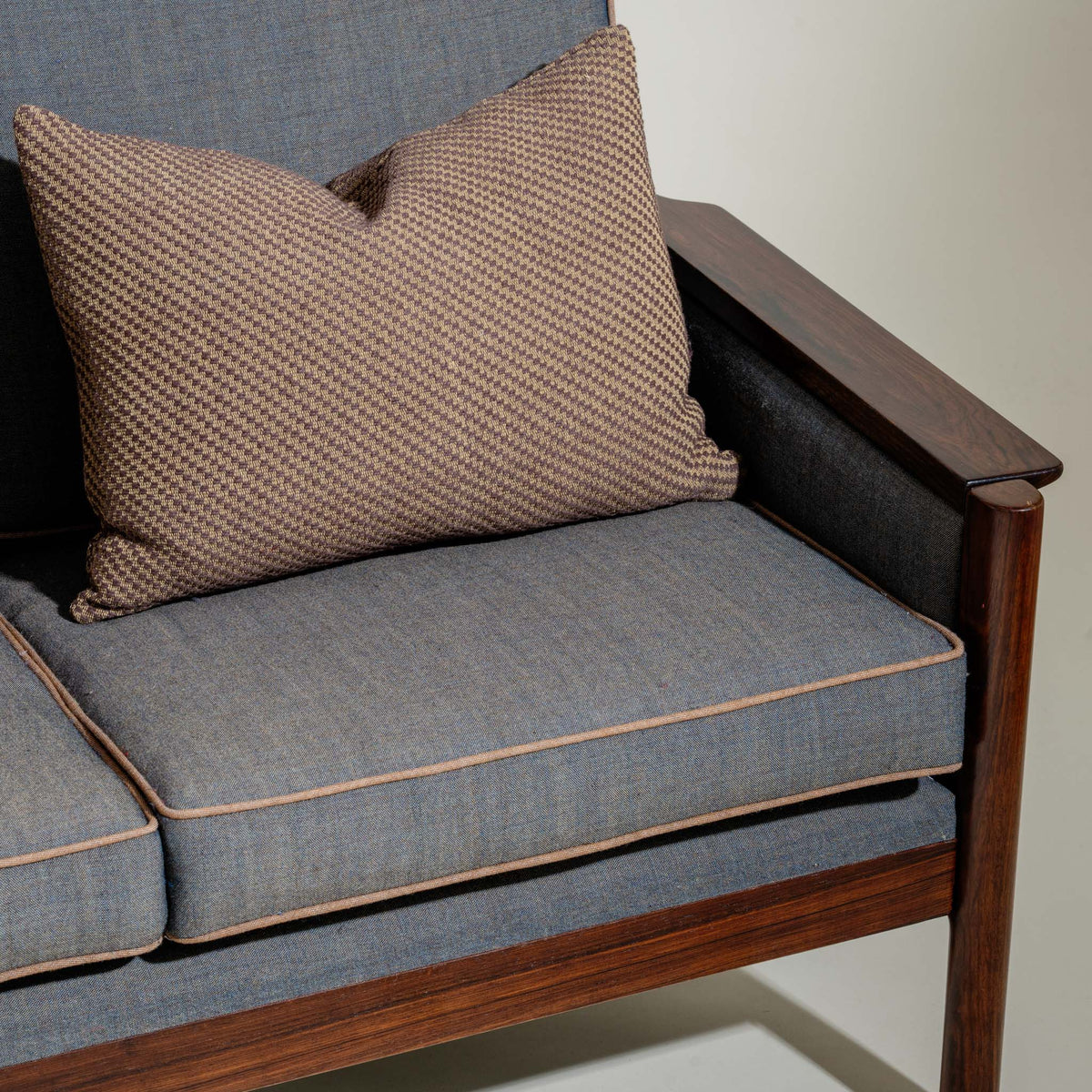Gray cushioned chair with a brown textured pillow on a plain background
