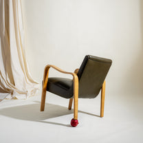 Modern chair with wooden frame and olive leather cushion against a white background