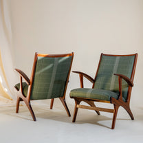 Pair of upholstered wooden armchairs with green plaid cushions on a neutral background