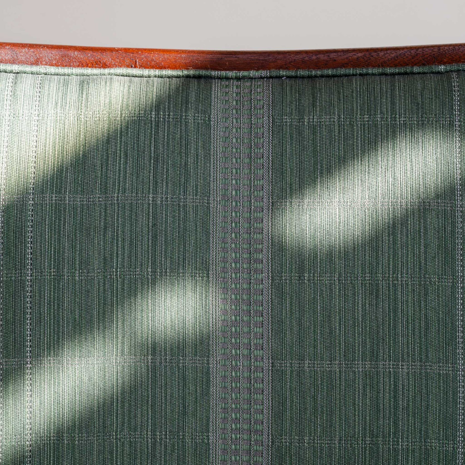 Close-up of a woven Jennifer Shorto fabric that the chair is upholstered with. The wooden frame is visible at the top of the image.