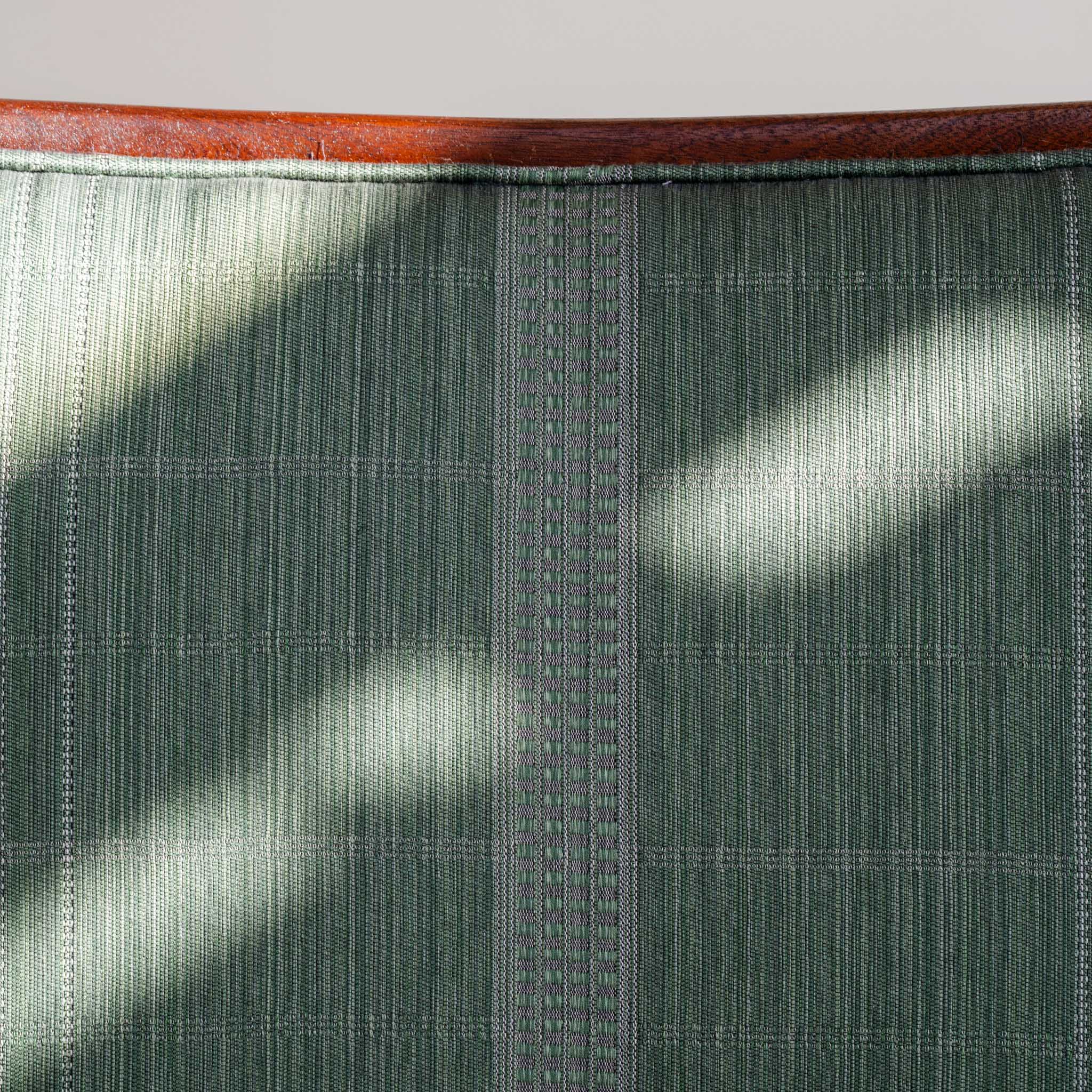 Close-up of a woven Jennifer Shorto fabric that the chair is upholstered with. The wooden frame is visible at the top of the image.