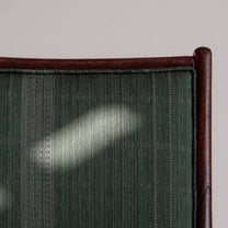Close-up of the green fabric surface on the chair with the wooden frame details surrounding it