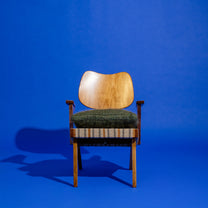 Wooden Russell Spanner chair with green cushion on a blue background