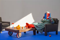 Person sitting on the parsons style chair, surrounded by oranges and a vase on a wooden table.