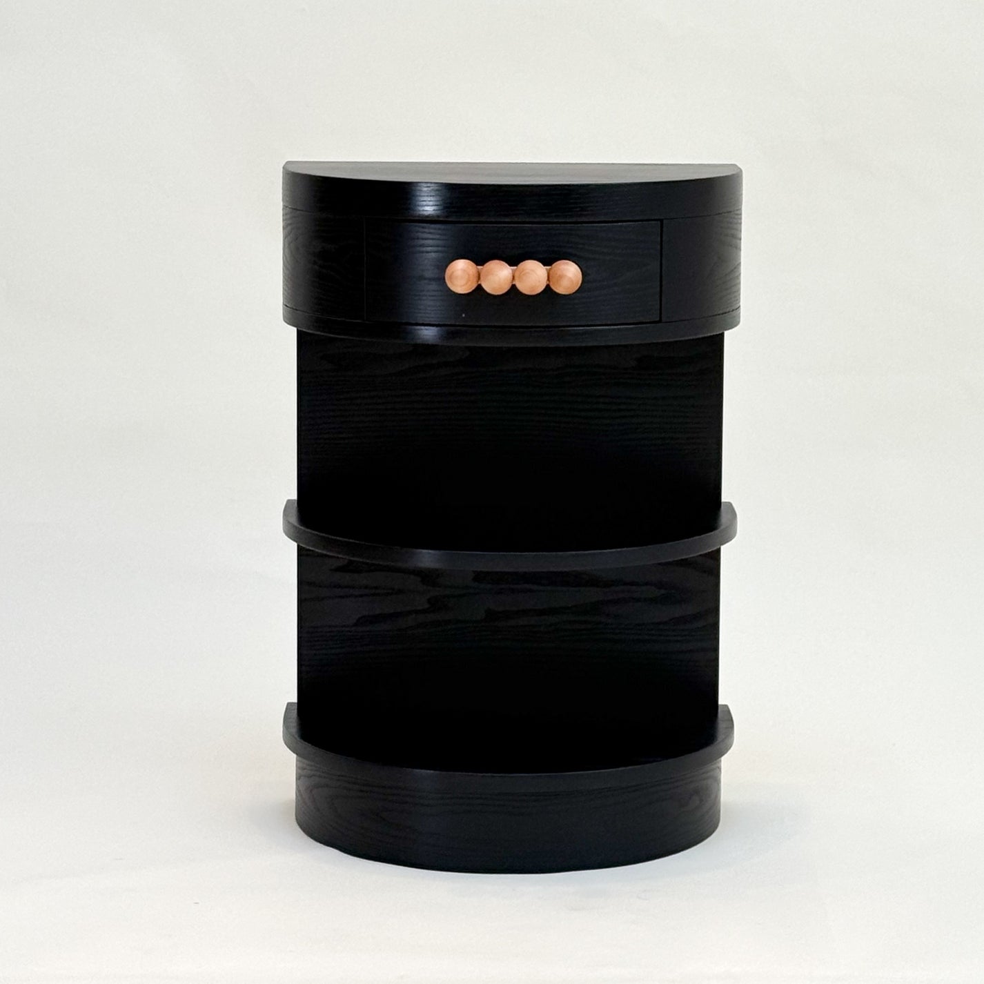 Black demi-lune nightstand with wooden knobs on a white background