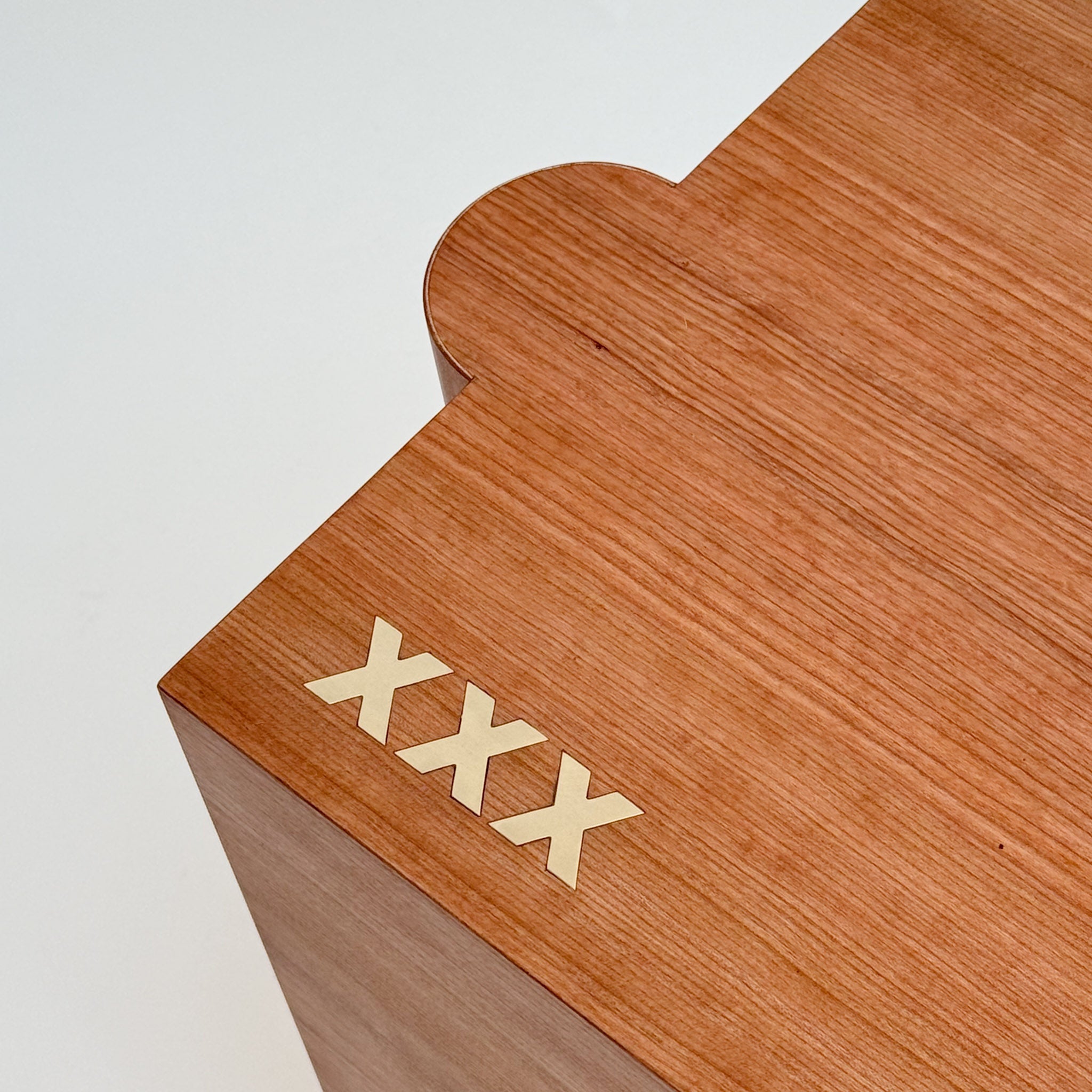 Close up of wooden table with 'XXX' engraving on a white background