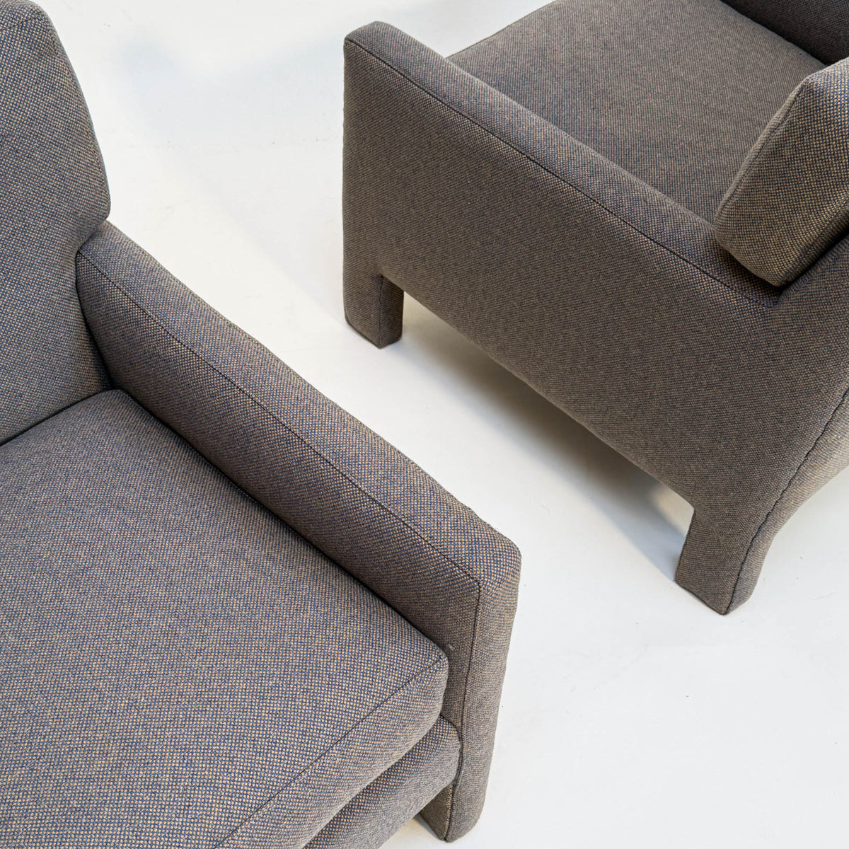 Two gray micro-checked Milo Baughman-style  upholstered chairs on a white background