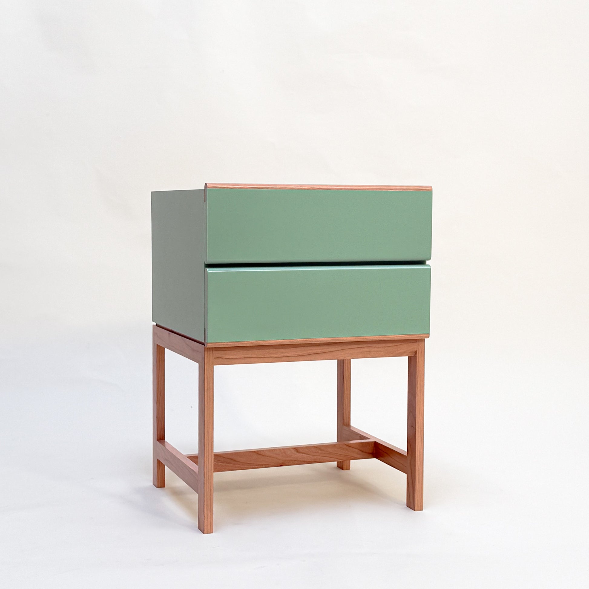 Handcrafted green nightstand with wooden legs on a white background