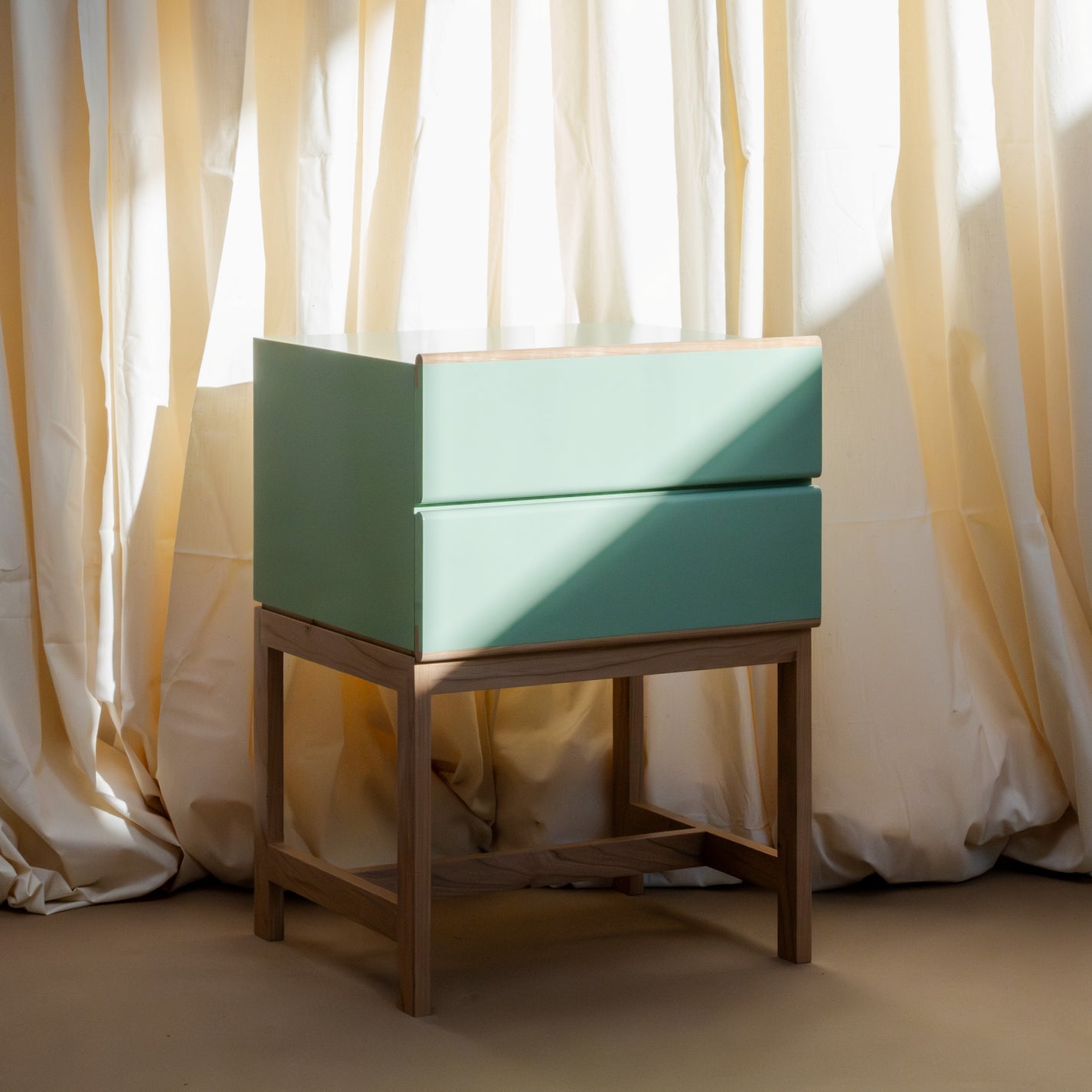 Elegant Wooden nightstand with a two drawer rectangular top section that is painted Farrow &amp; Ball Breakroom Green. The nightstand is open at the base with small wooden rectangular legs. There are four legs coming down from each corner with one parallel wooden piece toward the bottom half and one wooden piece at the same height at the bottom going across the space horizontally.