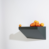 Geometric dark grey wall shelf with fruits on a white background