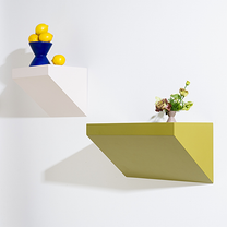 Two geometric wall shelves with a blue bowl of lemons and a vase of flowers on a white background