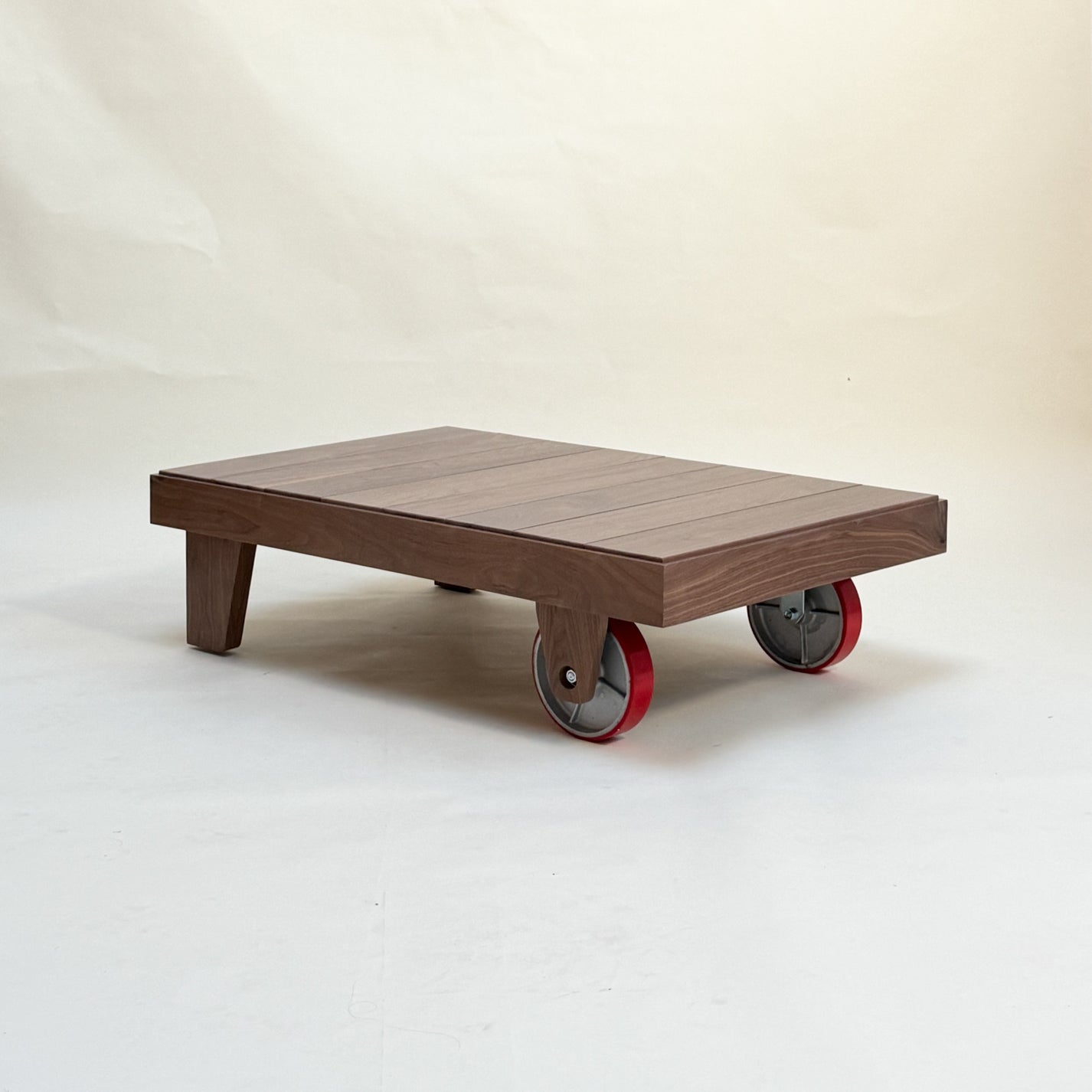 Wooden low coffee table with wheels on a plain background