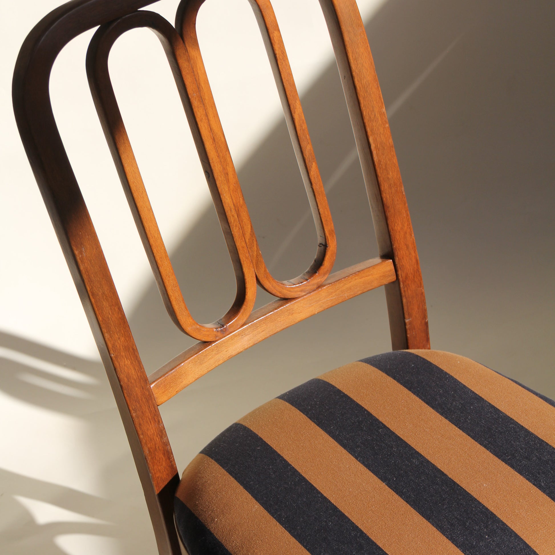 Wooden chair with striped cushion on a plain background