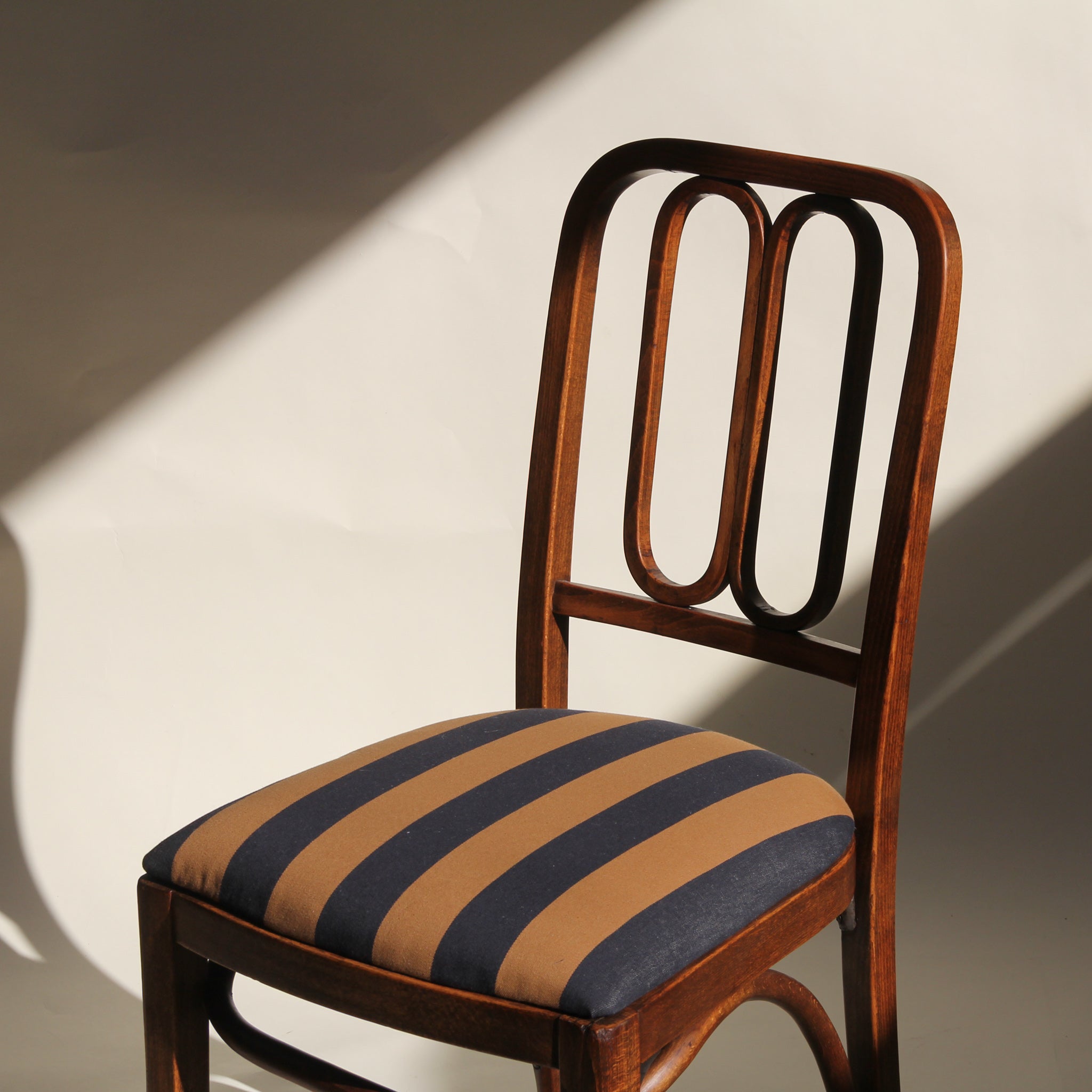 Wooden chair with striped cushion on a plain background