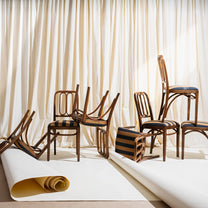 Wooden chairs with striped cushions arranged against a white curtain backdrop.