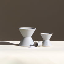 Three ceramic vessels on a white table with a darker background