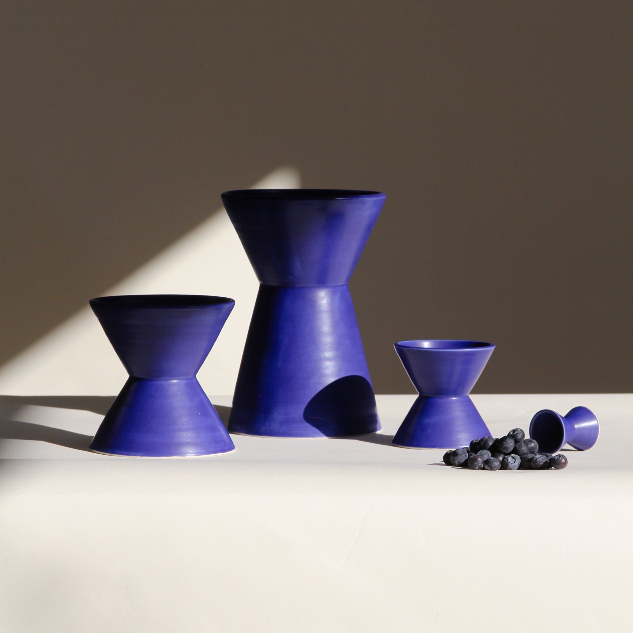 Set of blue ceramic vessels on a neutral background