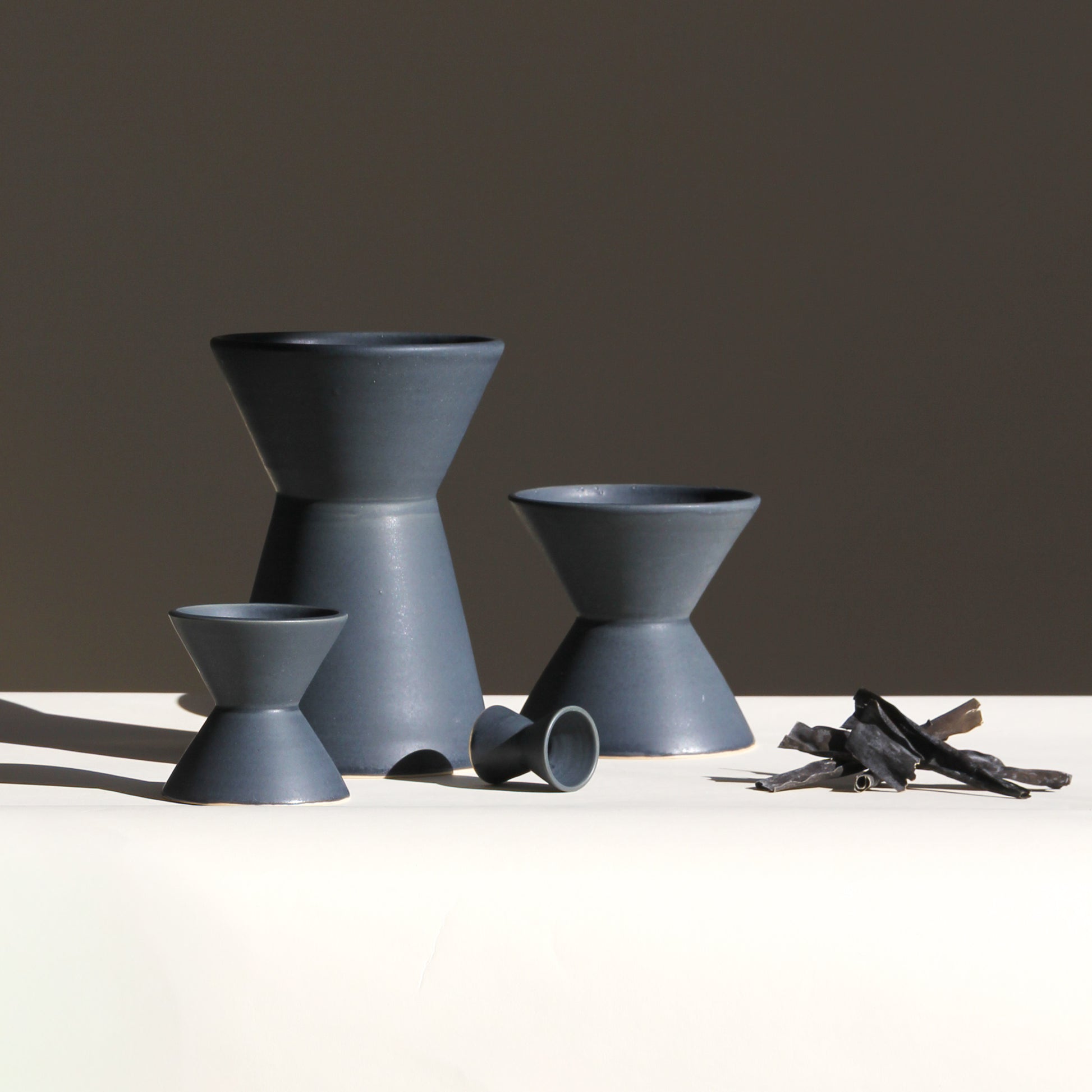Set of gray ceramic vessels on a white surface with a dark background