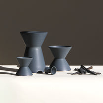 Set of gray ceramic vessels on a white surface with a dark background