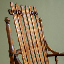 Close-up of a wooden rocking chair with a green background