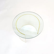 A modern round glass coffee table with a clear glass top and a sculptural, curved clear base, photographed from a top-down angle on a white background.