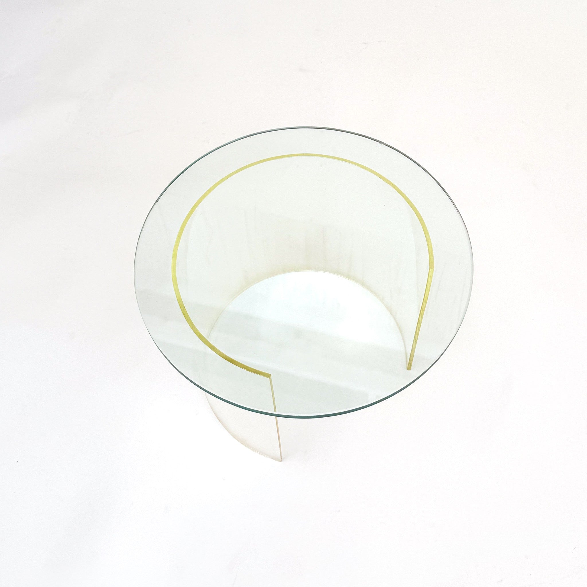 A modern round glass coffee table with a clear glass top and a sculptural, curved clear base, photographed from a top-down angle on a white background.