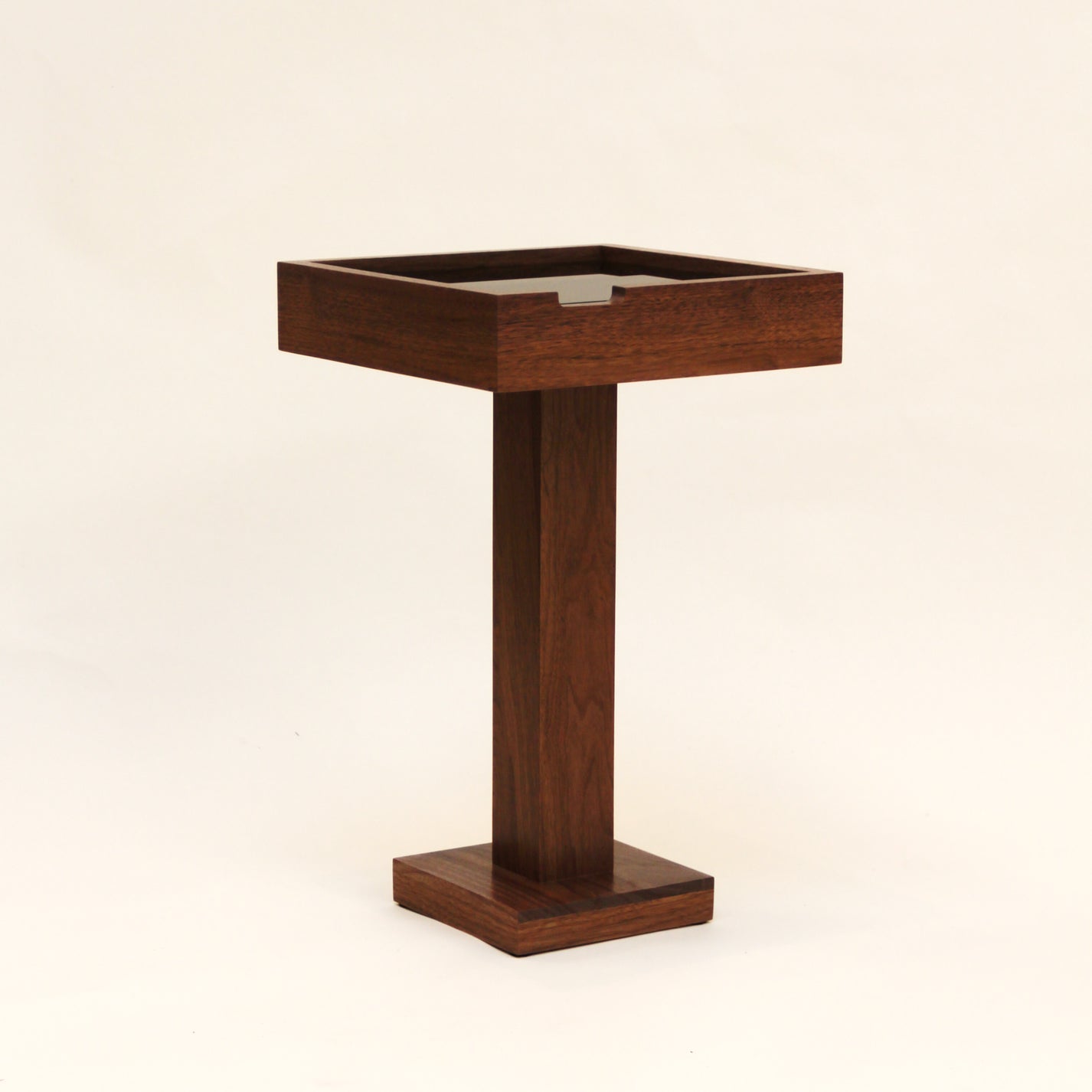 Handcrafted wooden pedestal coffee table with square top on a beige background